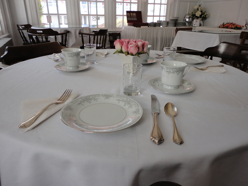An elegant breakfast table set with fine china, silver and fresh roses