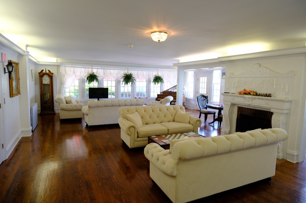 The living room with tufted cream sofas, fireplace and grand piano