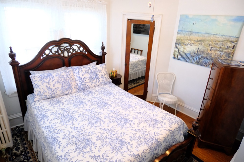 Guest room in blue toile with a floor mirror and beach painting